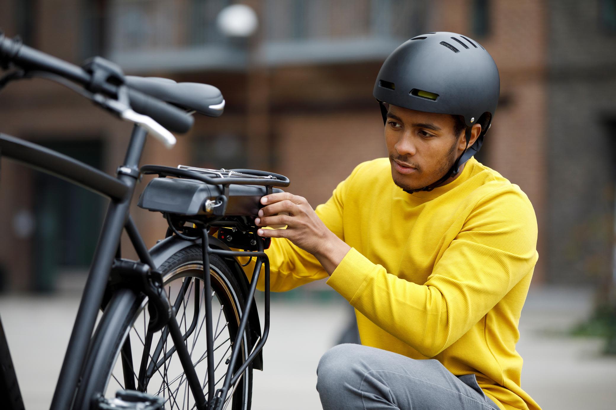 Die Technik auch beim günstigen E-Bike checken Mann mit gelbem Pulli untersucht sein E-Bike Fahrrad