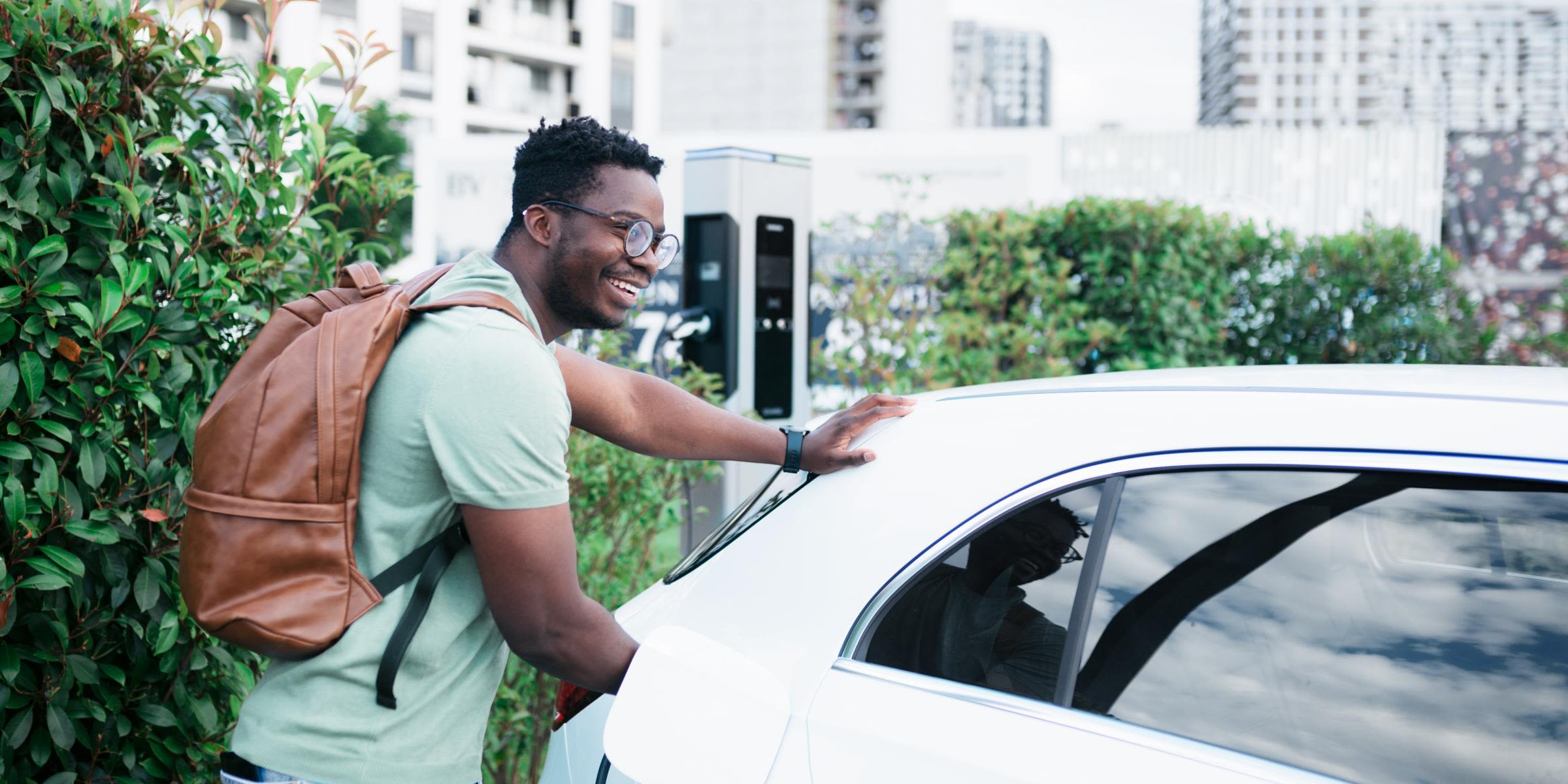 E-Auto ohne eigene Wallbox: Lohnt sich das? Ein Mann mit Rucksack lädt sein E-Auto an einer öffentlicher Ladesäule