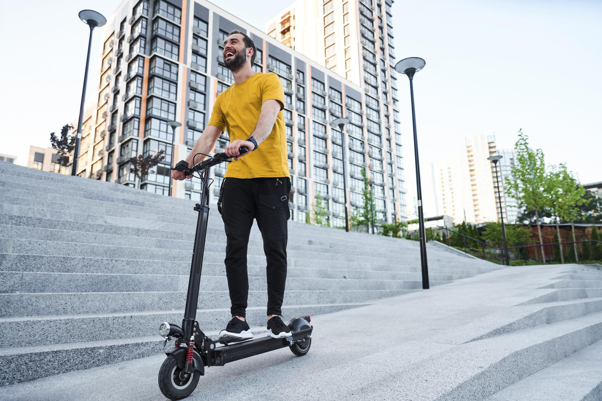 E-Scooter gibt's übrigens auch zu deinem Stromtarif von Yello Mann trägt ein gelbes Shirt und fährt auf einem E-Scooter.