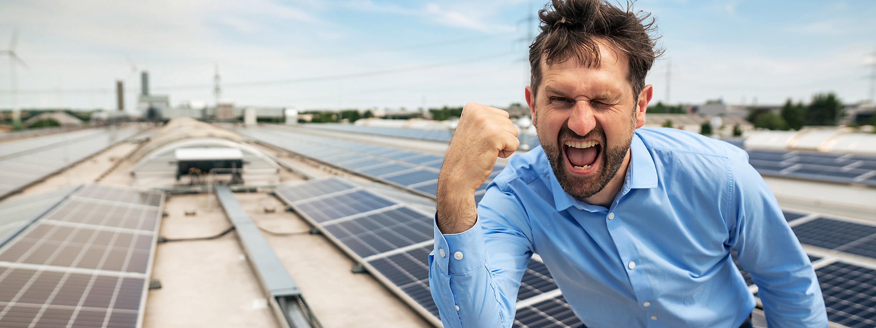 Ein Mann steht jubelnd auf einem Solar Dach