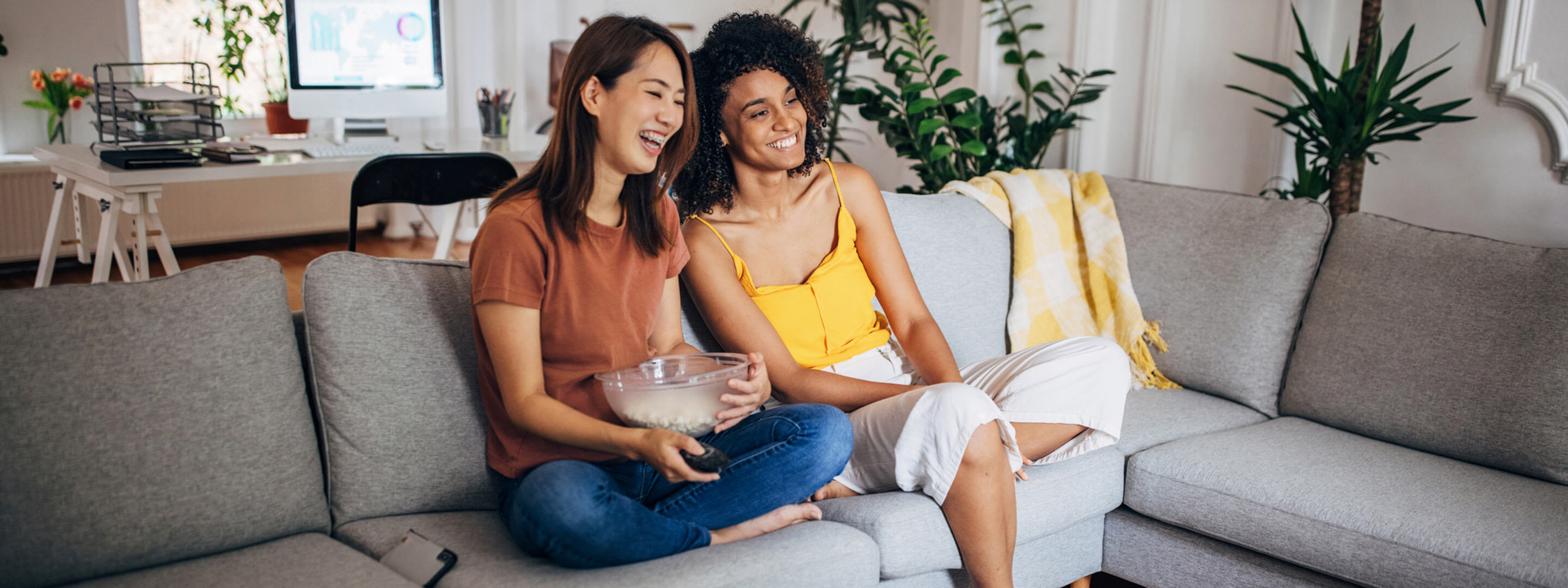Strom im Alltag ist so gar nicht langweilig Zwei Frauen sitzen mit Popcorn vor dem Fernseher