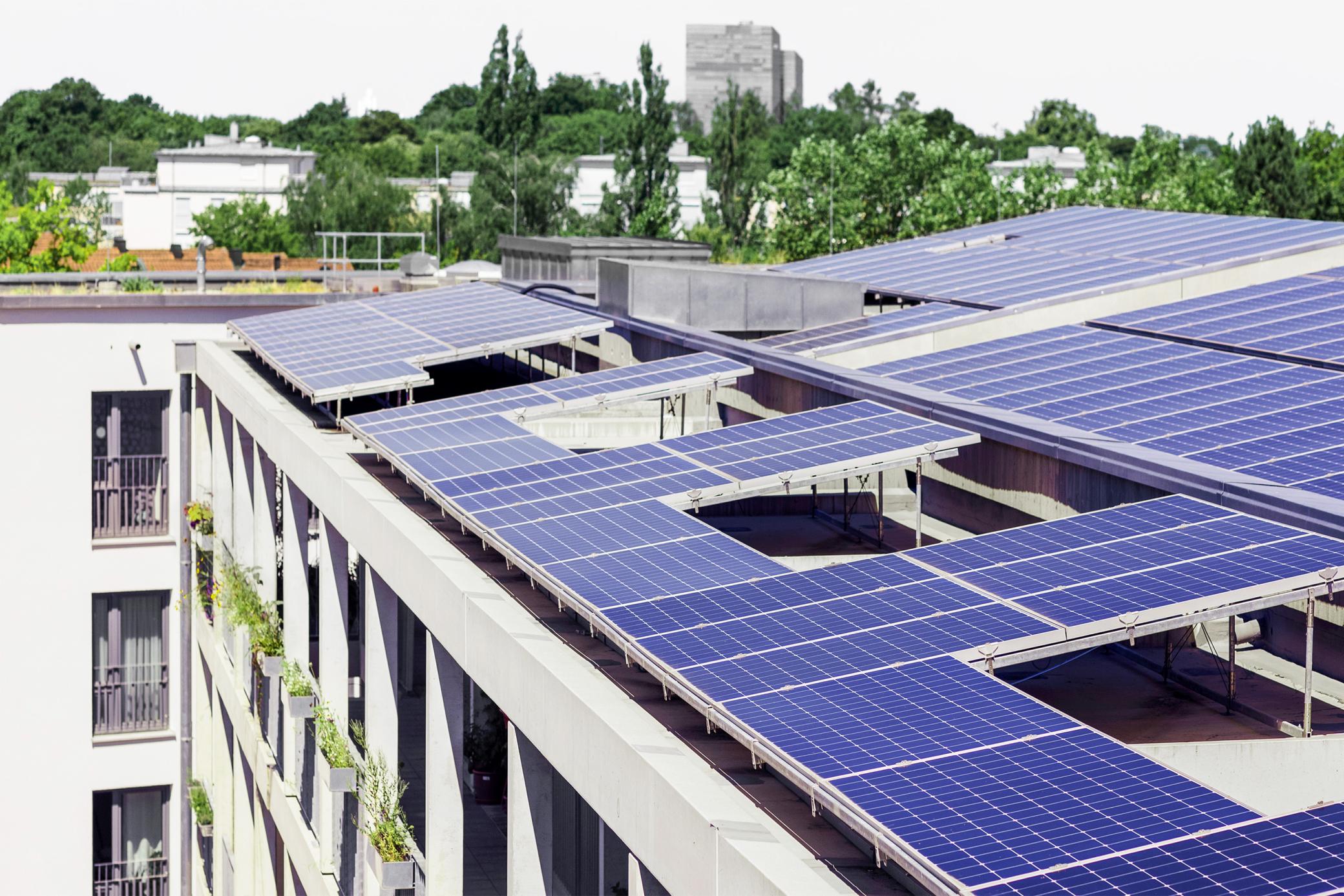 Blaue Solarmodule auf dem Dach eines Mehrfamilienhauses in der Stadt 