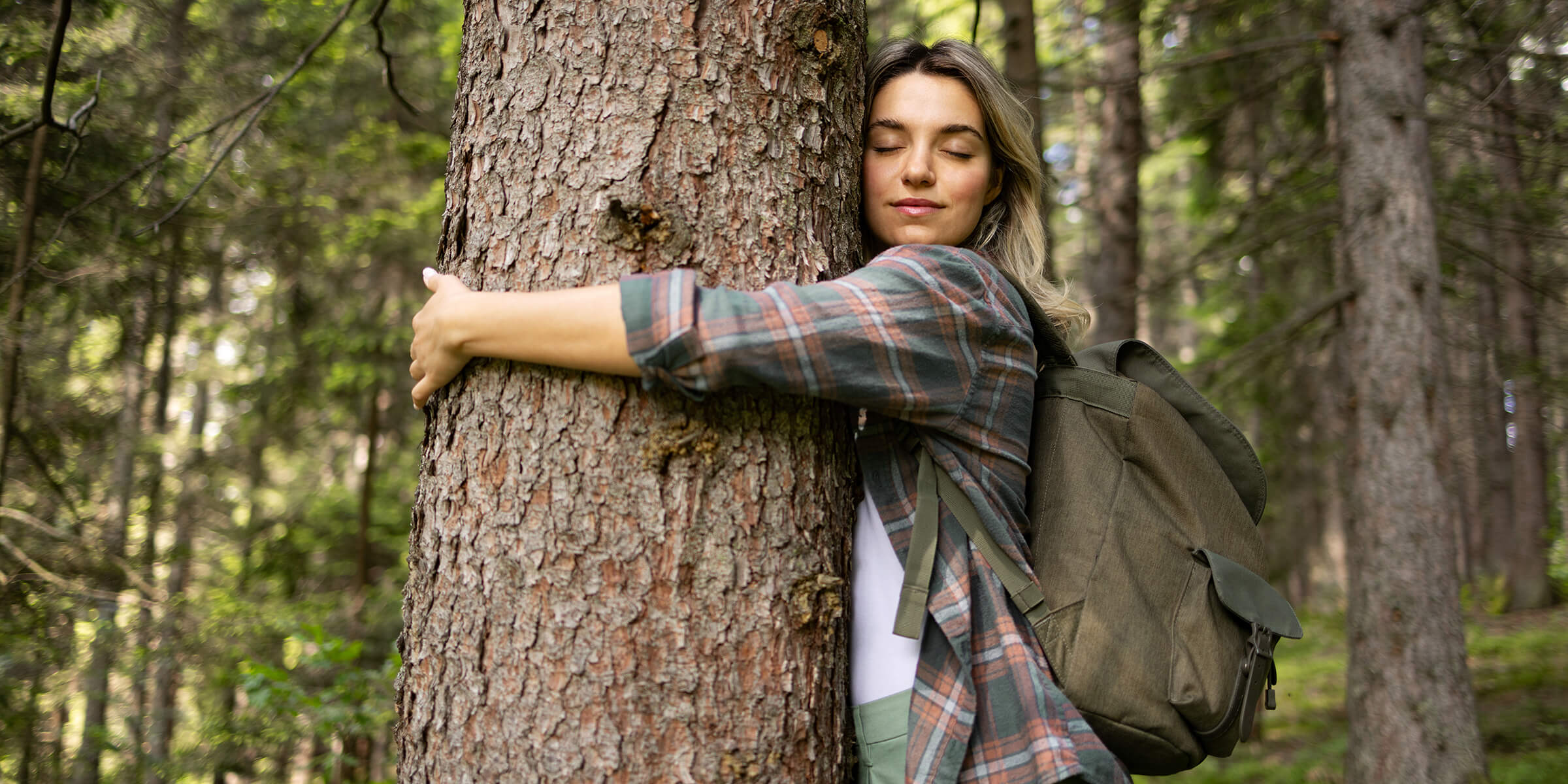 Für mehr Klimaschutz: Extra Abgabe für ausgestoßenes CO₂ Frau steht im Wald und umarmt einen Baum