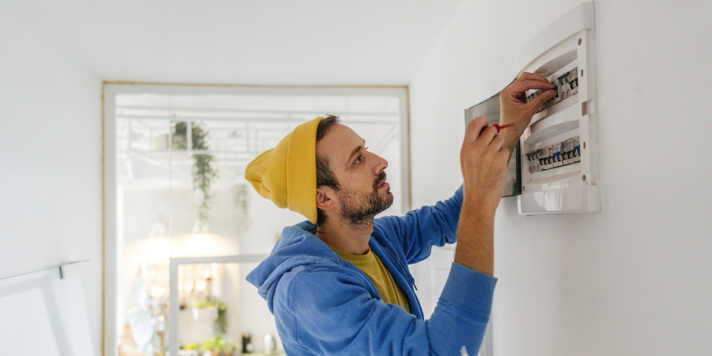 Strombegriffe einfach verstehen: Von Stromlieferant bis Netzbetreiber Junger Elektriker arbeitet an einen Sicherungskasten.