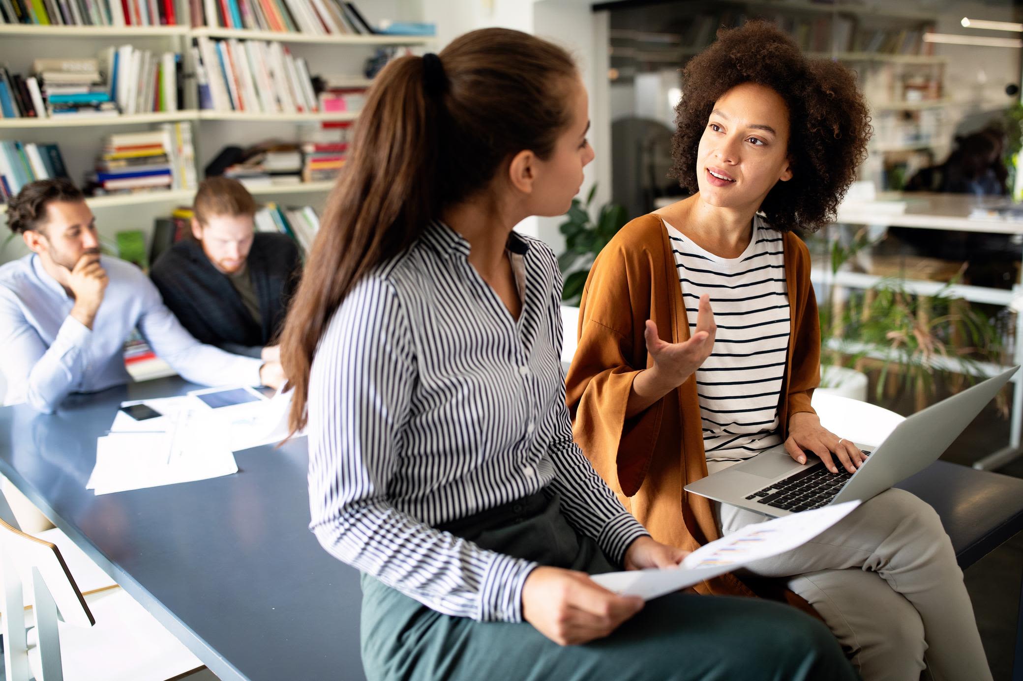 Wir erklären dir Themen rund um den Energiemarkt einfach Zwei Frauen unterhalten sich in der Bibliothek