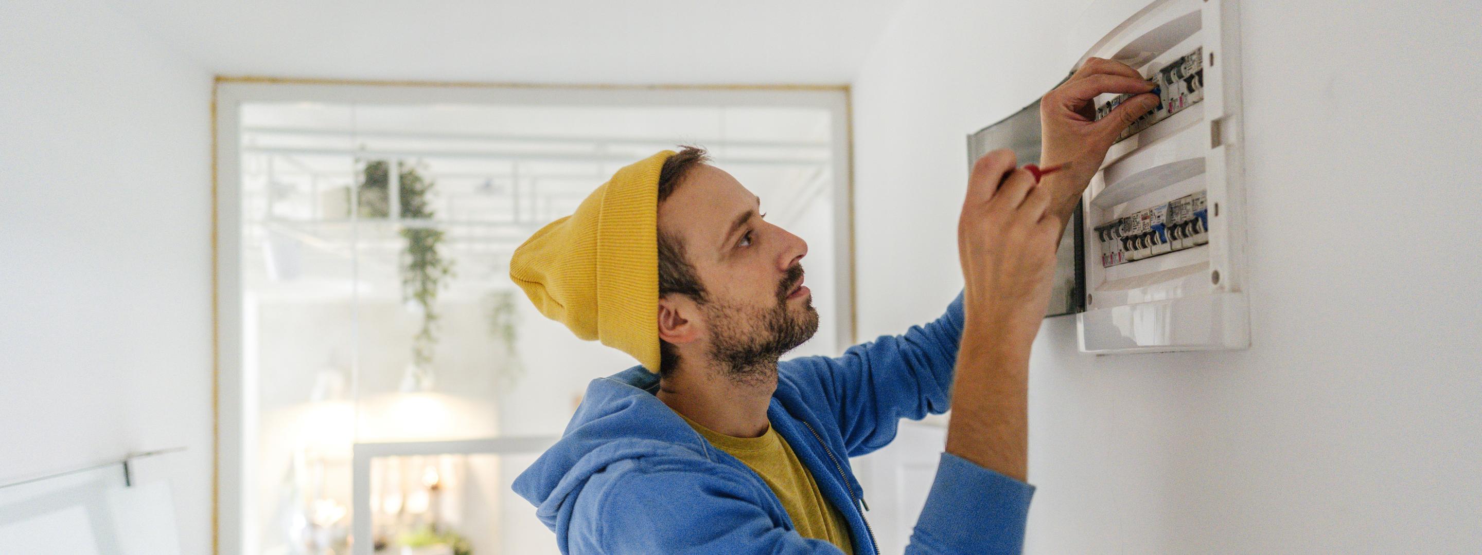 Junger Elektriker arbeitet an einen Sicherungskasten