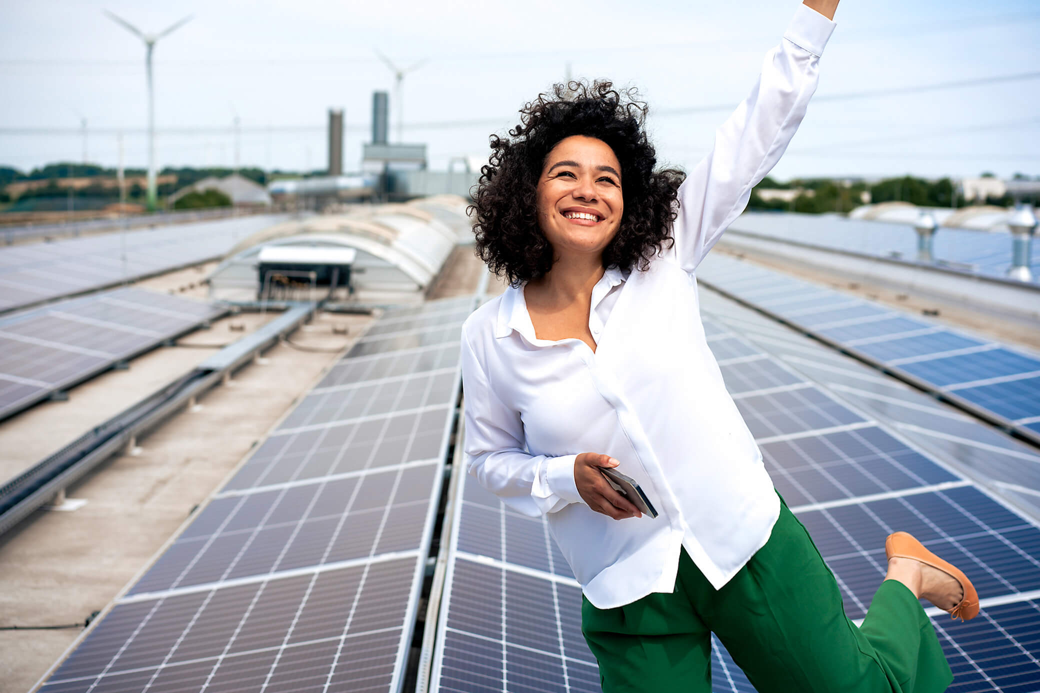 Eine Frau steht freudestrahlend auf einem Solar Dach.