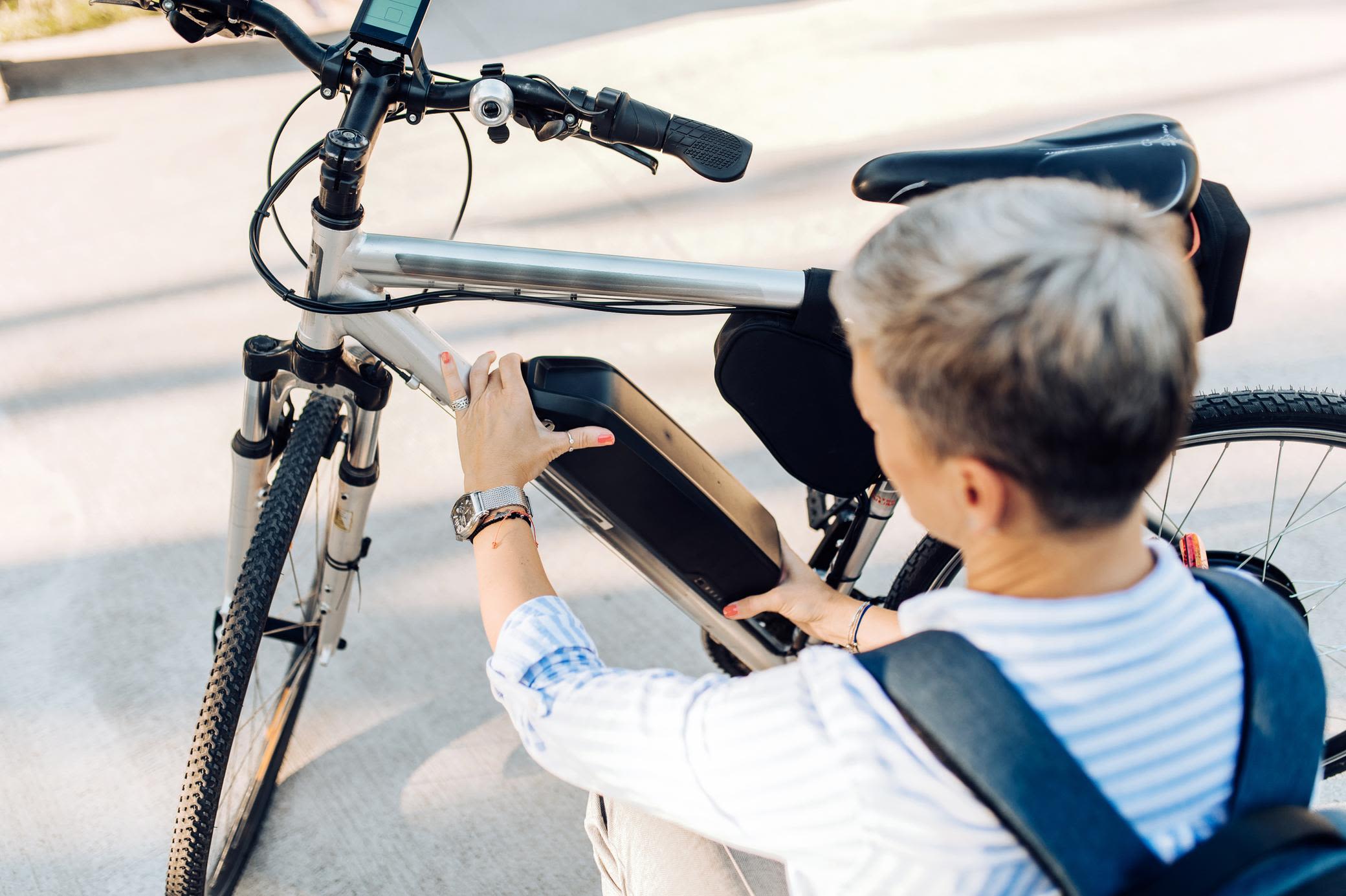 E-Bike gebraucht kaufen: Gut für dein Geldbeutel Frau wechselt die Batterie ihres E-Bike