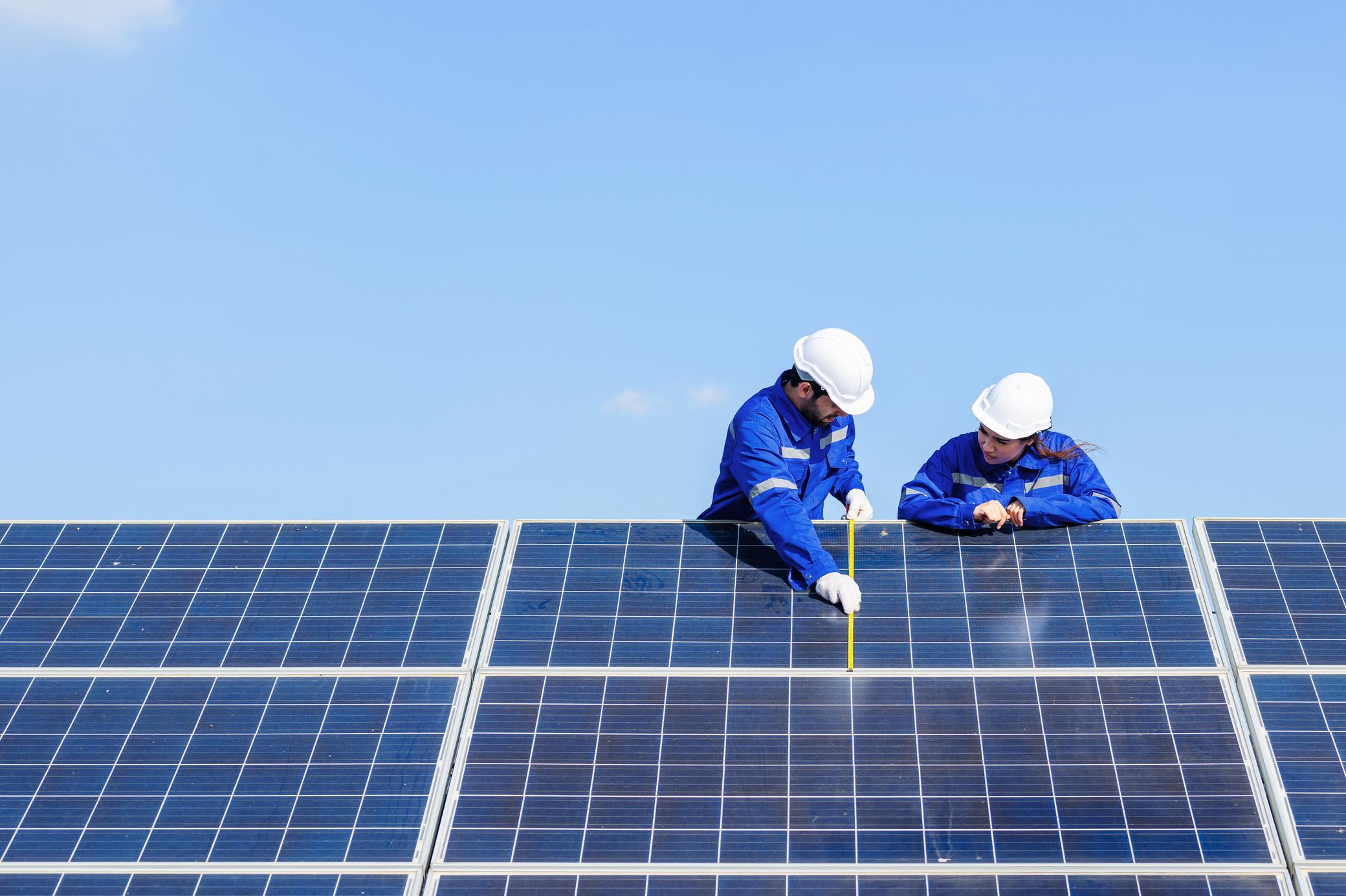 Zwei Techniker überprüfen Solaranlage auf einem Dach