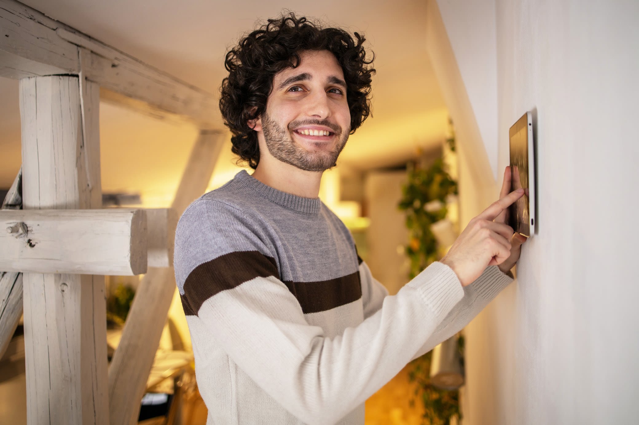 Ein HEMS optimiert den Energieverbrauch in deinem smarten Zuhause Mann steuert sein HEMS zuhause über ein Tablet an der Wand