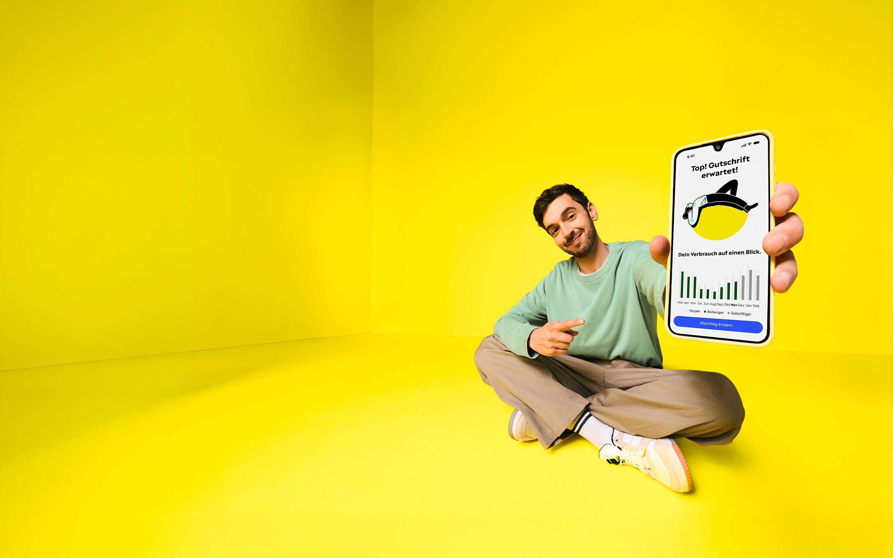 Yello App ist deine einfache Strom-App – gute Energie, 100 % digital Ein Mann lehnt an einem großen Handy, das die Yello App mit dem Stromverbrauch zeigt.