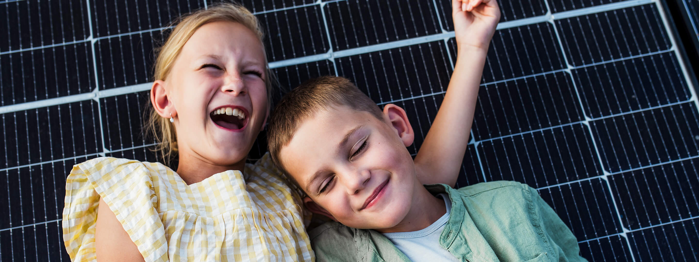 Familie lehnt fröhlich an einem Solarpanel und lacht
