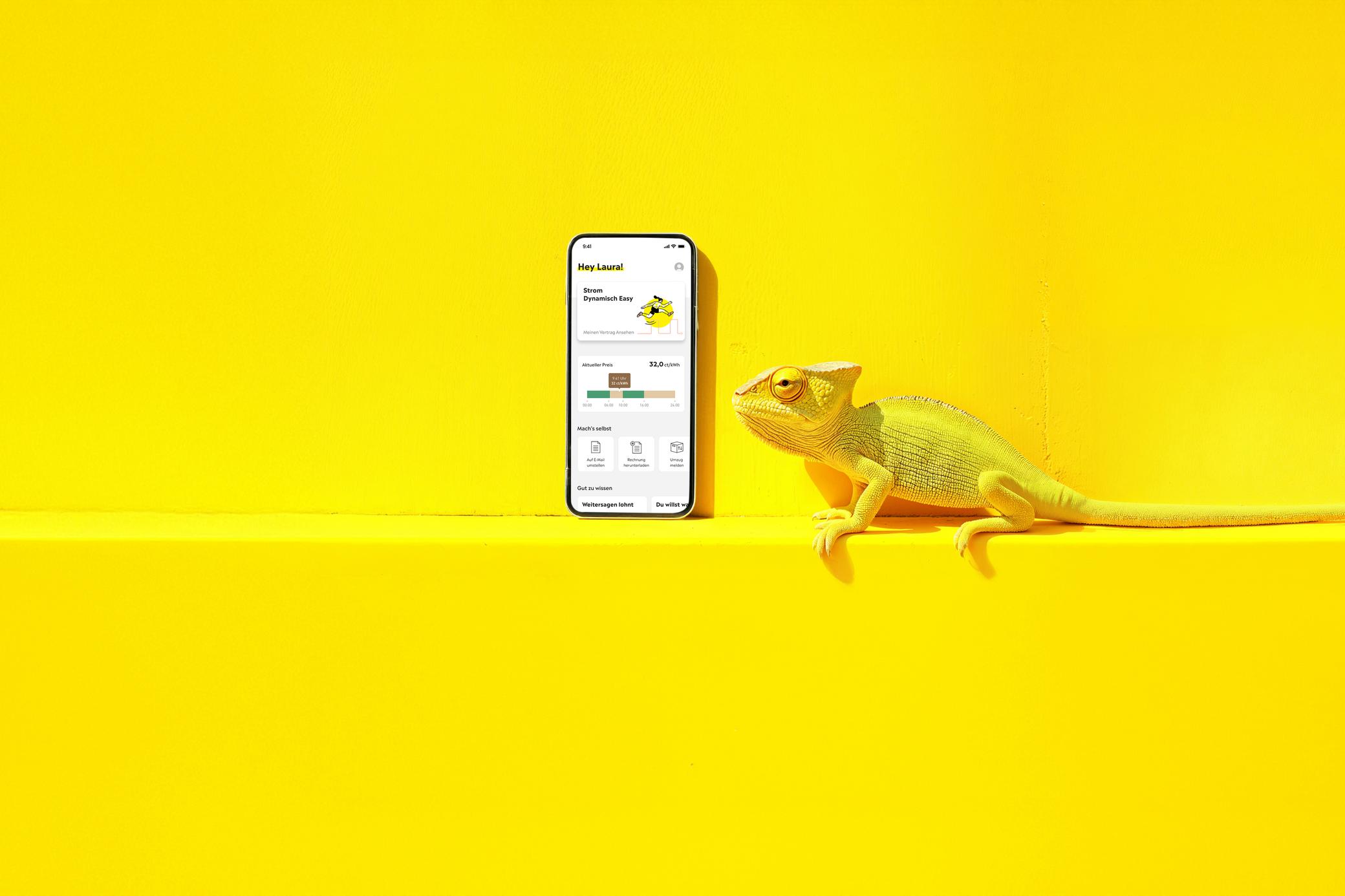 Gelbes Chamäleon schaut auf ein Handy mit Yello App - KI generiert