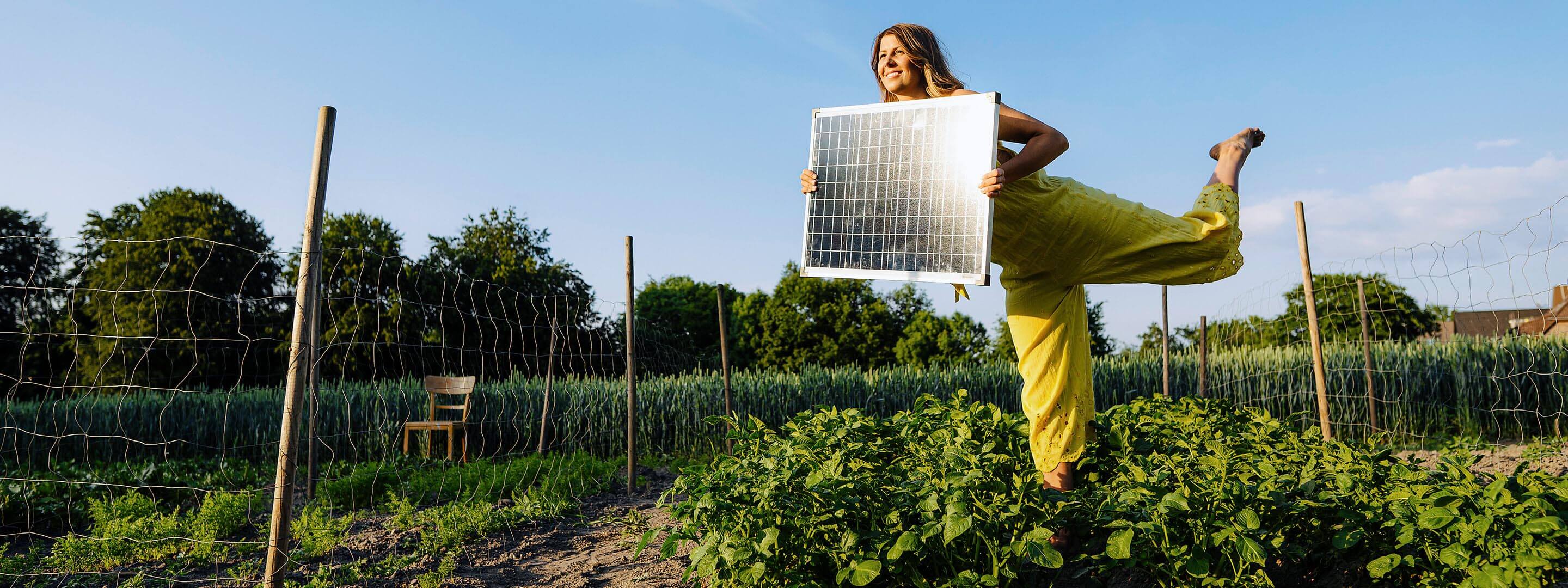 Erneuerbare Energien: Ein Game Changer für mehr Klimaschutz Frau mit Solarmodul in den Händen im Garten