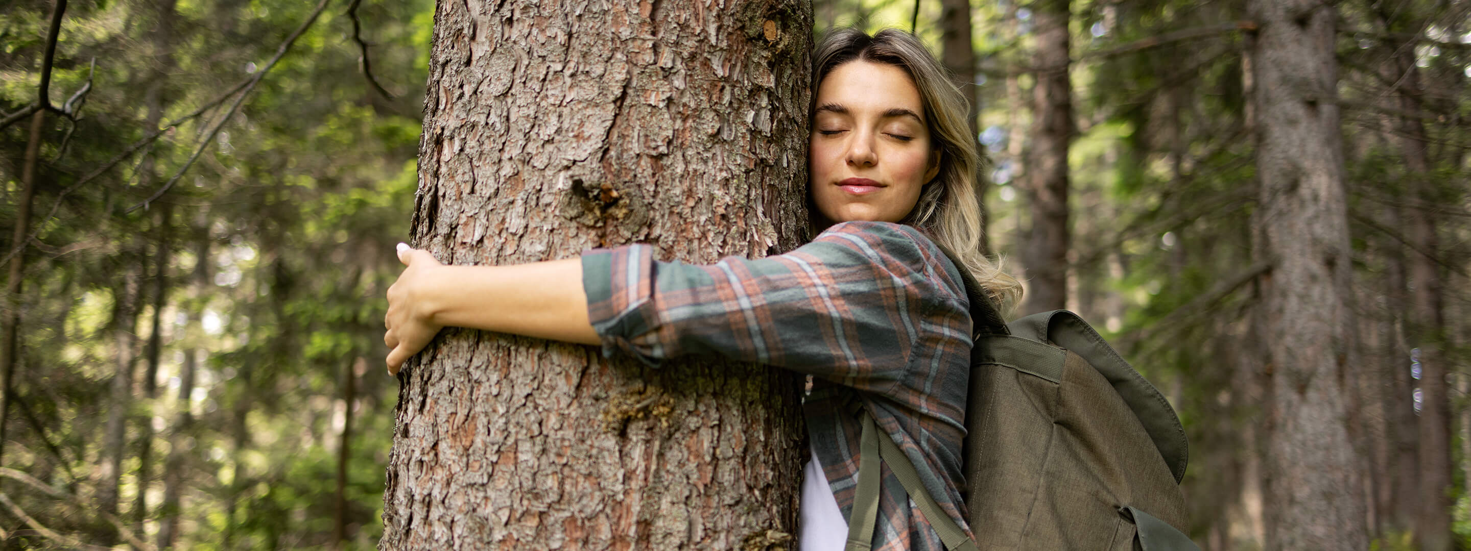 Extra Abgabe für ausgestoßenes CO₂ Frau steht im Wald und umarmt einen Baum