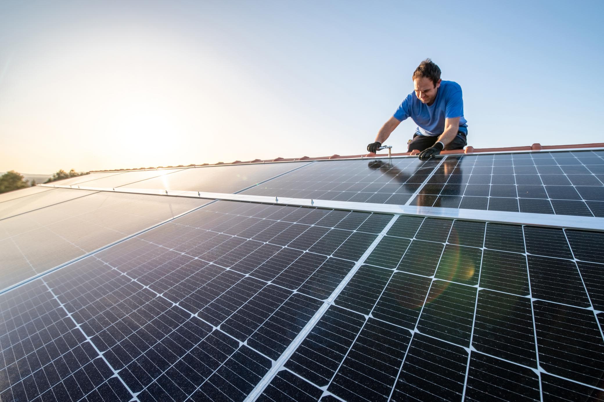 Eine Solaranlage auf dem eigenen Dach bringt viele Vorteile Mann installiert eine Photovoltaik-Anlage auf dem Dach