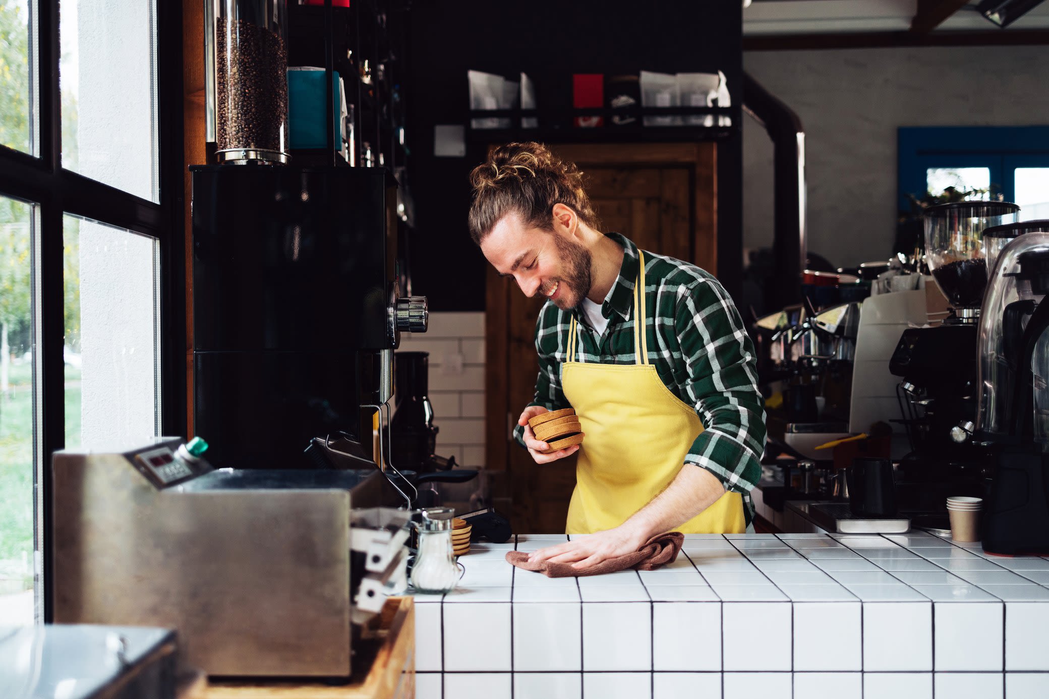Grüner Strom für dein Gewerbe kommt von Yello Mann im Cafe vor Barista Maschinen bereitet Kaffee für Kunden und Gäste vor