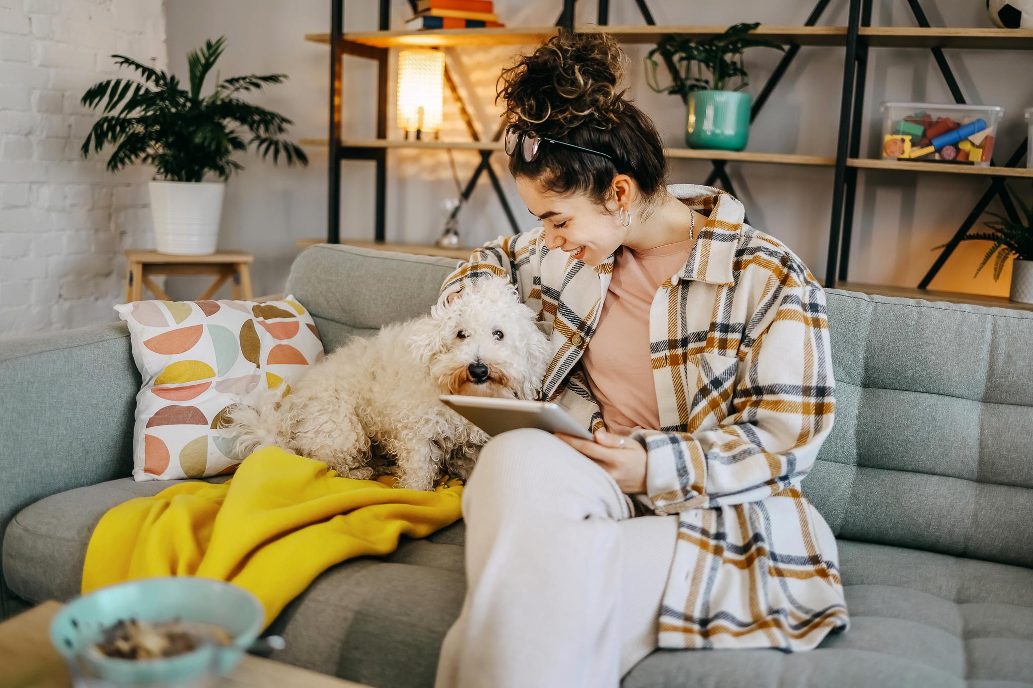 Frau kuschelt mit Hund auf dem Sofa