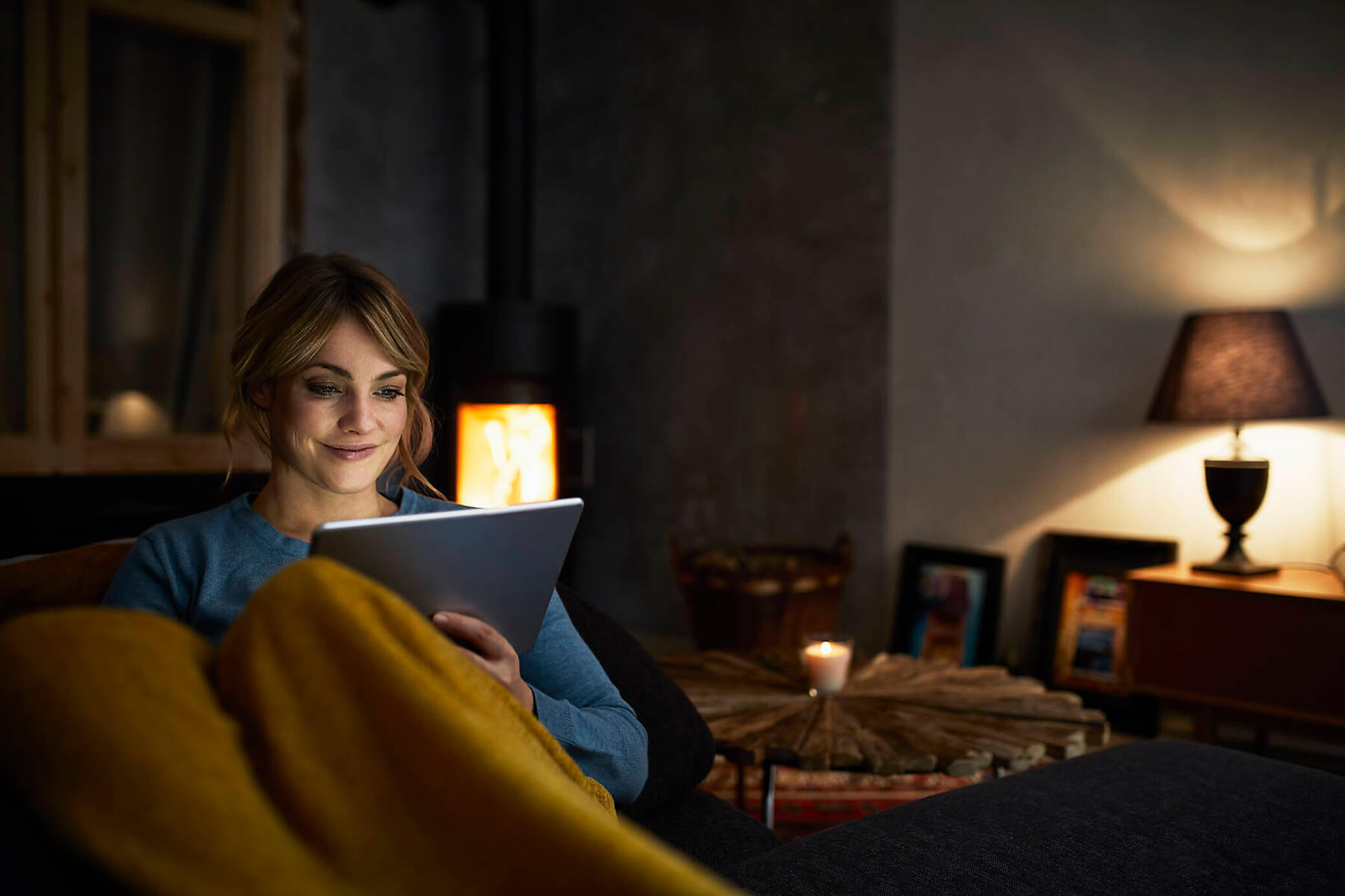 Frau schaut Abends bei gedimmten Licht aufs Tablet 