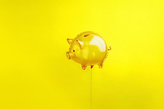 Gelbes Luftballon Sparschwein Ein gelbes Sparschwein in Luftballon Form schwebt vor gelbem Hintergrund.